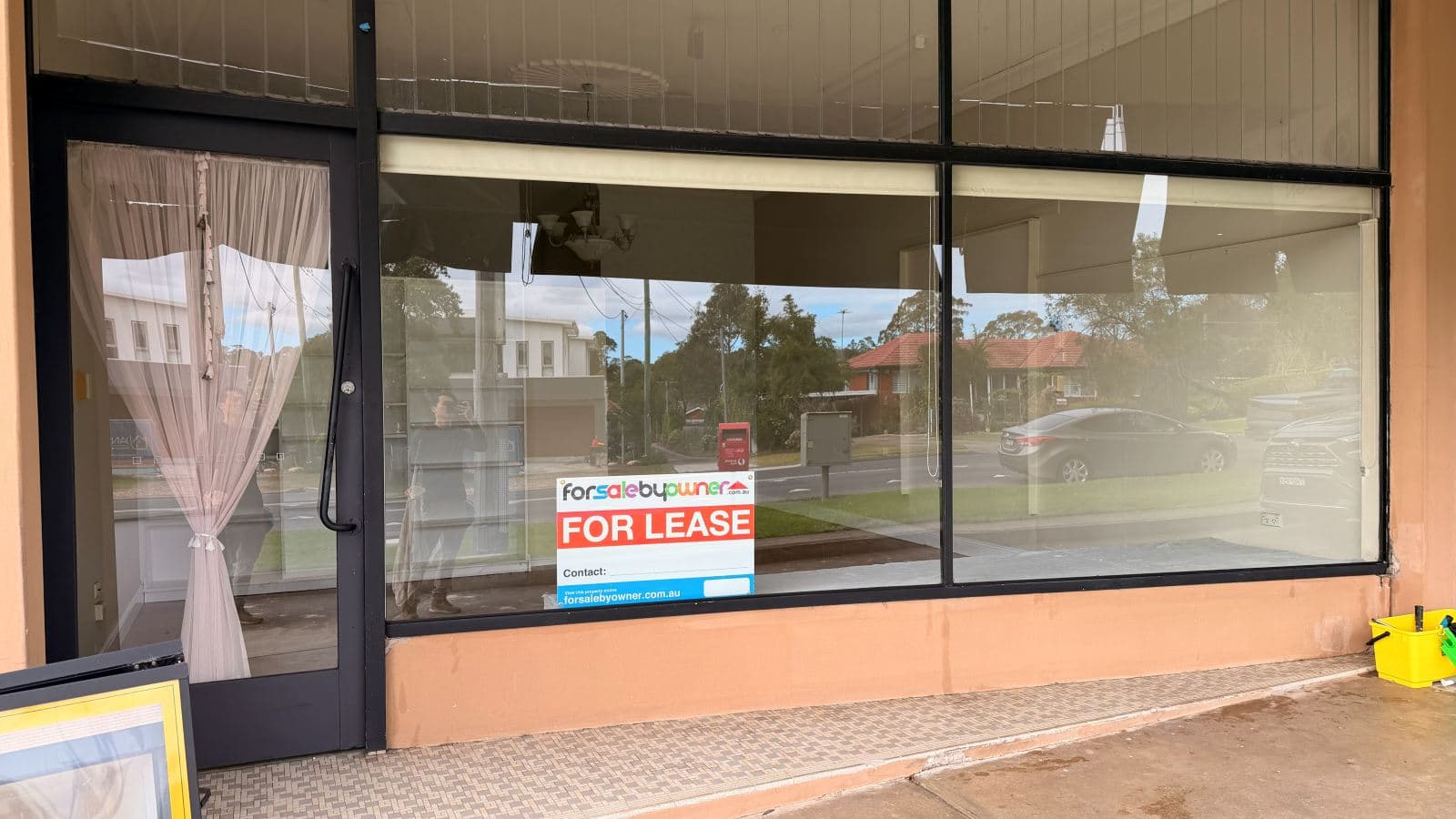 Technician cleaning shopfront glass at an Epping retail store